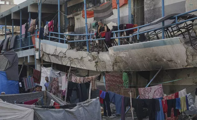 A displaced Palestinian man stands on a damaged balcony of a school used as a shelter, in Gaza City, Wednesday, Aug. 27, 2025. (AP Photo/Jehad Alshrafi)