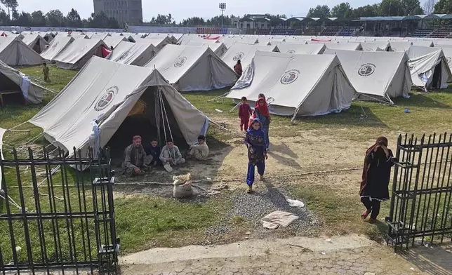 Internally Displaced People, who fled from their homes due to security forces launched a targeted operation against militants, walk at a camp set up in a sports complex in Khar, the main town of Bajaur, a northwestern Pakistani district bordering Afghanistan, Tuesday, Aug. 12, 2025. (AP Photo/Anwarullah Khan)