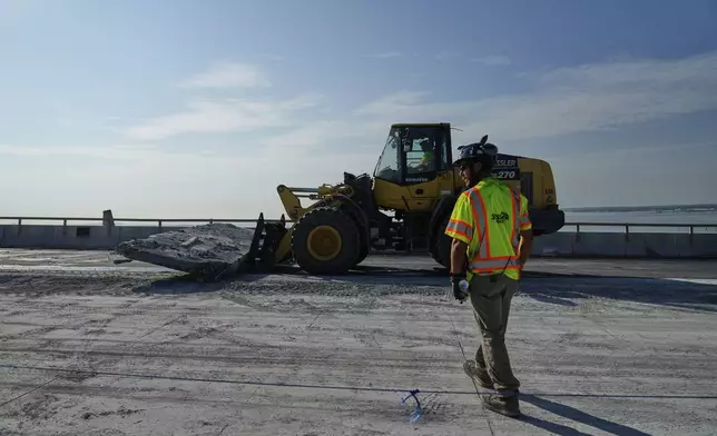 A demolition crew removes a slab of concrete from the remaining portions of the Francis Scott Key Bridge, Wednesday, July 30, 2025, in Baltimore. (AP Photo/Stephanie Scarbrough)