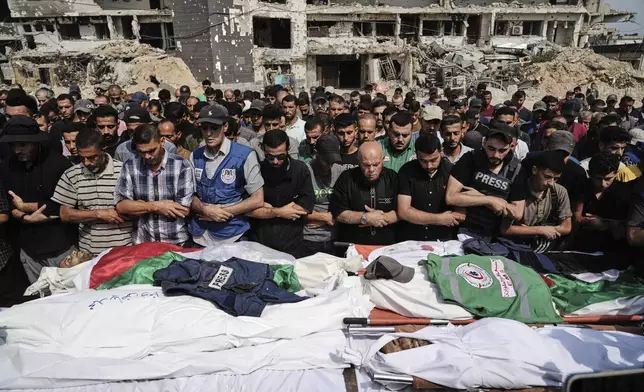 CORRECTS SURNAME TO QREIQEH, INSTEAD OF QUREIQA - Palestinians pray over the bodies of journalists, including Al Jazeera correspondents Anas al-Sharif and Mohamed Qreiqeh, who were killed in an Israeli airstrike, during their funeral outside Gaza City's Shifa hospital complex, Monday, Aug. 11, 2025. (AP Photo/Jehad Alshrafi)