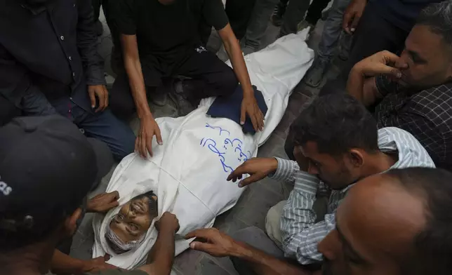 Colleagues and friends mourn over the body Al Jazeera correspondent Mohamed Qureiqa who was killed with his colleague Anas al-Sharif and other journalists by an Israeli airstrike, at Shifa Hospital in Gaza City Monday, Aug. 11, 2025. (AP Photo/Jehad Alshrafi)