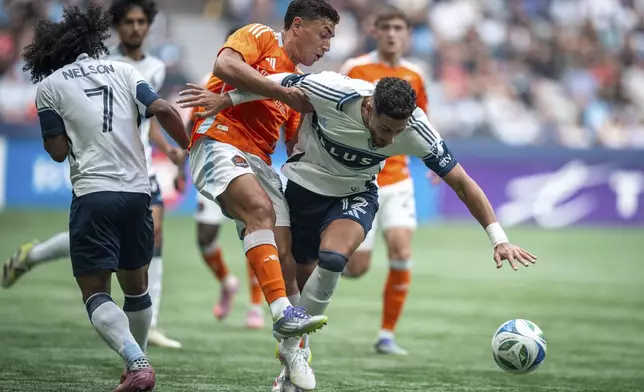 Houston Dynamo's Ezequiel Ponce (and Vancouver Whitecaps' Belal Halbouni (12) collide as they vie for the ball during the first half of an MLS soccer match in Vancouver, British Columbia, Sunday, Aug. 17, 2025. (Ethan Cairns/The Canadian Press via AP)