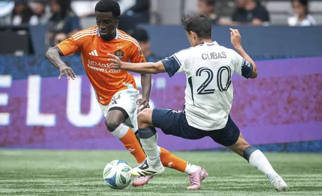 Houston Dynamo's Brooklyn Raines runs past Vancouver Whitecaps' Andres Cubas (20) during the first half of an MLS soccer match in Vancouver, British Columbia, Sunday, Aug. 17, 2025. (Ethan Cairns/The Canadian Press via AP)