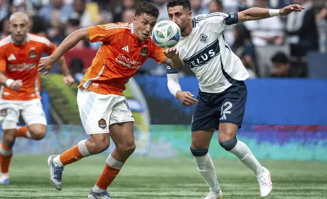 Houston Dynamo's Ezequiel Ponce and Vancouver Whitecaps' Belal Halbouni (12) vie for the ball during the first half of an MLS soccer match in Vancouver, British Columbia, Sunday, Aug. 17, 2025. (Ethan Cairns/The Canadian Press via AP)