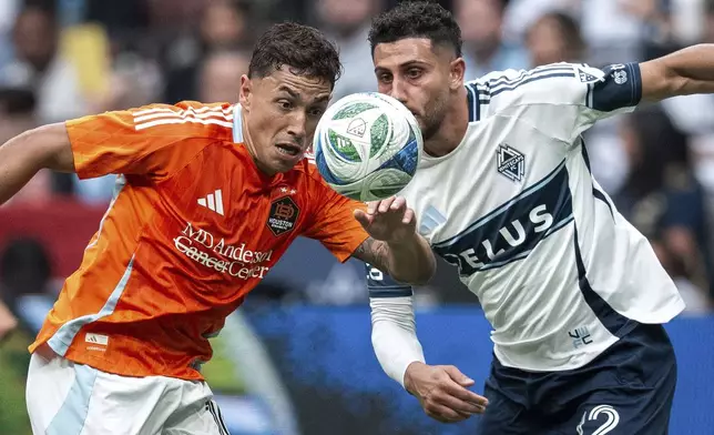 Houston Dynamo's Ezequiel Ponce and Vancouver Whitecaps' Belal Halbouni vie for the ball during the first half of an MLS soccer match in Vancouver, British Columbia, Sunday, Aug. 17, 2025. (Ethan Cairns/The Canadian Press via AP)