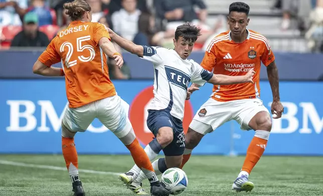 Vancouver Whitecaps' Andres Cubas, Houston Dynamo's Griffin Dorsey, and Antinio Carlos vie for the ball during the first half of an MLS soccer match in Vancouver, British Columbia, Sunday, Aug. 17, 2025. (Ethan Cairns/The Canadian Press via AP)