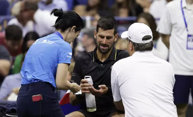 Novak Djokovic, of Serbia, talks with trainers during the third round match against Cameron Norrie, of Great Britain, of the U.S . Open tennis championships, Friday, Aug. 29, 2025, in New York. (AP Photo/Adam Hunger)