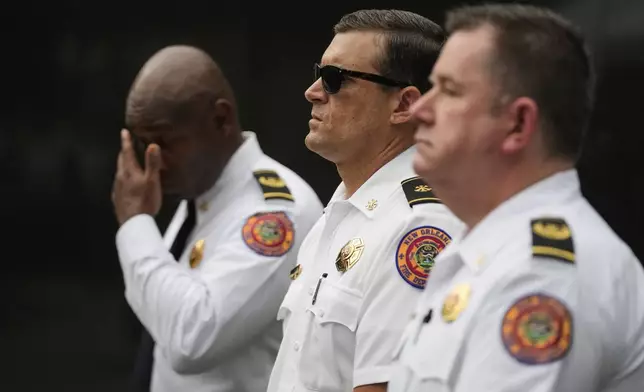 New Orleans fire chiefs Zachary Gremillion, left, Ray Casey, and Byron Casey, right, stand at attention during a wreath laying event to commemorate the 20th anniversary of Hurricane Katrina, at the Hurricane Katrina Memorial in Charity Hospital Cemetery in New Orleans, Friday, Aug. 29, 2025. (AP Photo/Gerald Herbert)