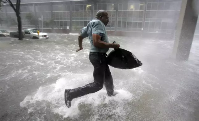 FILE - Arnold James tries to keep his feet as a strong gust nearly blows him over as makes his way on foot to the Louisiana Superdome in New Orleans, Aug. 29, 2005. (AP Photo/Dave Martin, File)