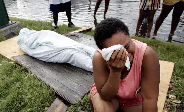 FILE - Evelyn Turner cries alongside the body of her common-law husband, Xavier Bowie, after he died in New Orleans, Aug. 30, 2005. (AP Photo/Eric Gay)