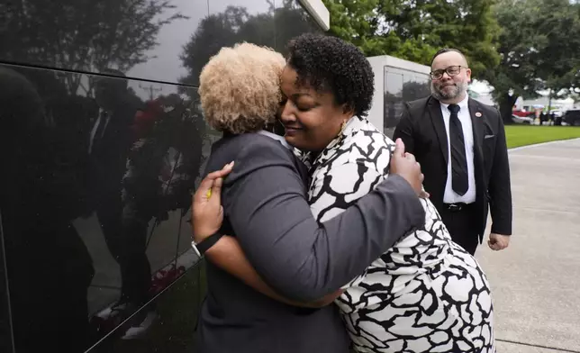Jasminne Navarre hugs Constance Osum, left, during a wreath laying event to commemorate the 20th anniversary of Hurricane Katrina, at the Hurricane Katrina Memorial in Charity Hospital Cemetery in New Orleans, Friday, Aug. 29, 2025. (AP Photo/Gerald Herbert)