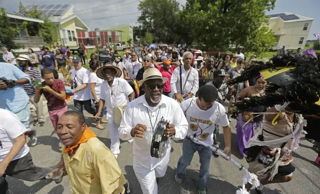 FILE - A second-line parade makes its way past homes built by Brad Pitt's Make It Right Foundation to commemorate the 10th anniversary of Hurricane Katrina, in the Lower 9th Ward in New Orleans, Aug. 29, 2015. (AP Photo/Gerald Herbert, File)