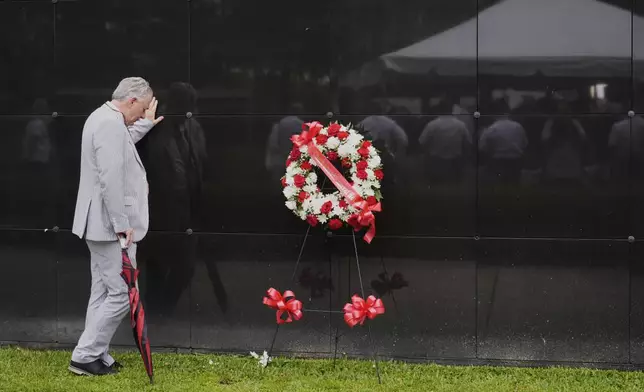 Gary Wainwright pauses at tombs for unidentified victims during a wreath laying event to commemorate the 20th anniversary of Hurricane Katrina, at the Hurricane Katrina Memorial in Charity Hospital Cemetery in New Orleans, Friday, Aug. 29, 2025. (AP Photo/Gerald Herbert)