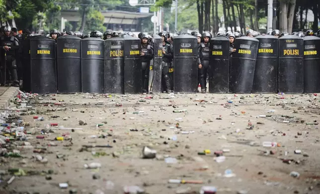 Debris litter the street as police officers take their position following violent protests against lawmakers' allowance and police brutality after a delivery rider was allegedly run over by a police armored vehicle during clashes between riot police and students protesters, in Jakarta, Indonesia, Saturday, Aug. 30, 2025. (AP Photo/Dita Alangkara)