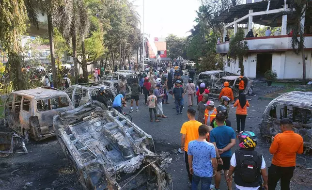 People inspect the wreckages of cars burned in a protest against lavish allowances given to parliament members in Makassar, South Sulawesi, Indonesia, Saturday, Aug. 30, 2025. (AP Photo/ Masyudi Firmansyah)