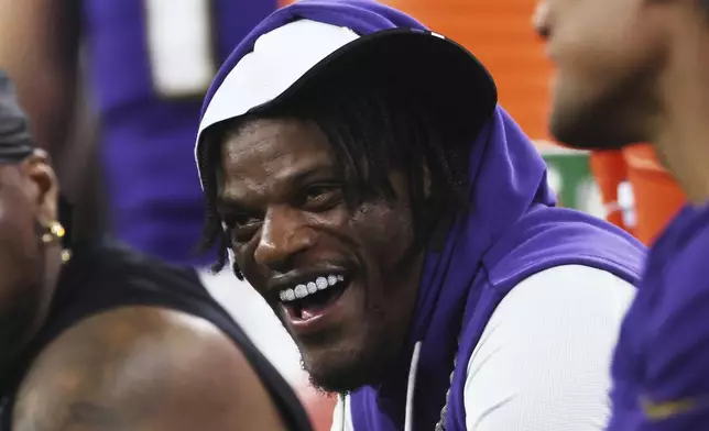 Baltimore Ravens quarterback Lamar Jackson laughs as he talks with teammates on the sideline in the first half of a preseason NFL football game against the Dallas Cowboys Saturday, Aug. 16, 2025, in Arlington, Texas. (AP Photo/Gareth Patterson)