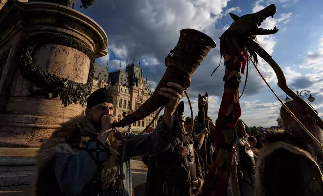 A man blows a horn as history buffs wearing Dacian warrior and Roman soldiers outfits march in Iasi, Romania, Friday, July 11, 2025 ahead of the Getodava historical reenactment festival. (AP Photo/Andreea Alexandru)