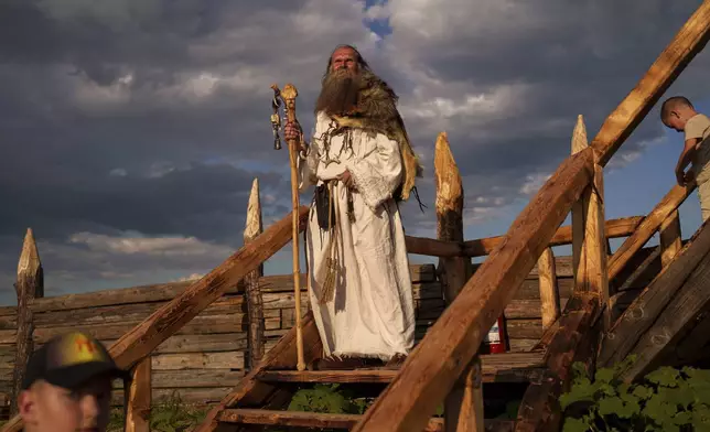 A man wearing a Dacian spiritual leader outfit stands on the steps of a Getic fortress replica in Poiana, Romania, Saturday, July 12, 2025 during the Getodava historical reenactment festival. (AP Photo/Vadim Ghirda)