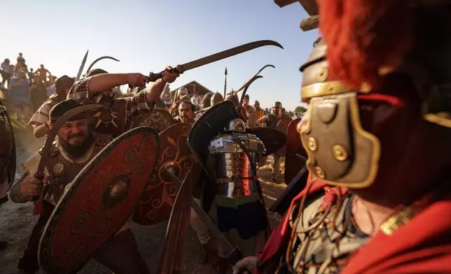 Members of historical reenactment groups wearing Dacian warrior and Roman soldiers outfits, clash in Poiana, Romania, Sunday, July 13, 2025, during the Getodava historical reenactment festival. (AP Photo/Vadim Ghirda)