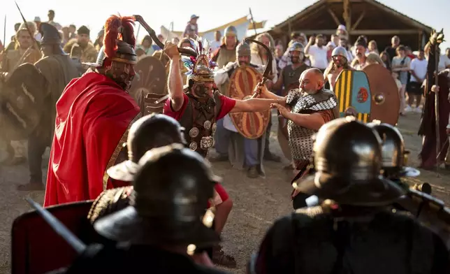 Members of historical reenactment groups wearing Dacian warrior and Roman soldiers outfits, clash in Poiana, Romania, Sunday, July 13, 2025, during the Getodava historical reenactment festival. (AP Photo/Vadim Ghirda)