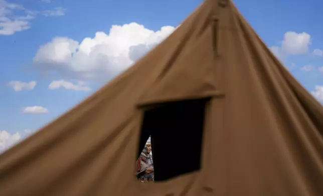 A man of the Legio X Gemina Coh II, Roman era military historical group with members from the Czech Republic and Slovakia, stands behind a tent in Poiana, Romania, Saturday, July 12, 2025, during the Getodava historical reenactment festival. (AP Photo/Andreea Alexandru)