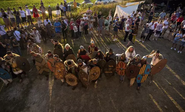 People watch as members of historical reenactment groups wearing Dacian warrior and Roman soldiers outfits, clash in Poiana, Romania, Sunday, July 13, 2025, during the Getodava historical reenactment festival. (AP Photo/Andreea Alexandru)