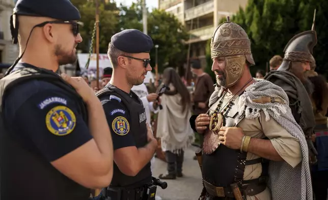 A man wearing a Dacian warrior outfits speaks to Romanian gendarmes in Iasi, Romania, Friday, July 11, 2025 ahead of the Getodava historical reenactment festival. (AP Photo/Vadim Ghirda)