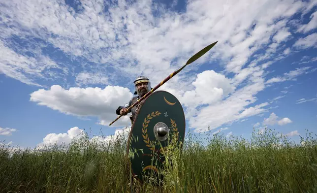 Andrej Miklanek of the Legio X Gemina Coh II, Roman era military historical group with members from the Czech Republic and Slovakia, strikes a pose in Poiana, Romania, Saturday, July 12, 2025, during the Getodava historical reenactment festival. (AP Photo/Andreea Alexandru)