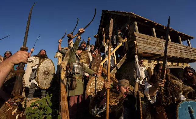 Members of historical reenactment groups wearing Dacian warrior outfits, scream before a battle in Poiana, Romania, Sunday, July 13, 2025, during the Getodava historical reenactment festival. (AP Photo/Andreea Alexandru)