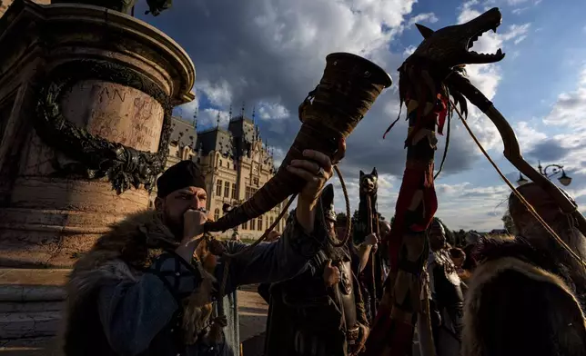 A man blows a horn as history buffs wearing Dacian warrior and Roman soldiers outfits march in Iasi, Romania, Friday, July 11, 2025 ahead of the Getodava historical reenactment festival. (AP Photo/Andreea Alexandru)