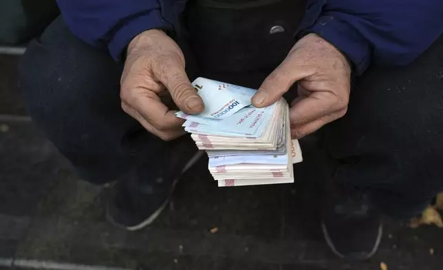 FILE - A street money exchanger poses for a photo without showing his face as he counts Iranian banknotes at a commercial district in downtown Tehran, Iran, Friday, Dec. 23, 2022. (AP Photo/Vahid Salemi, File)