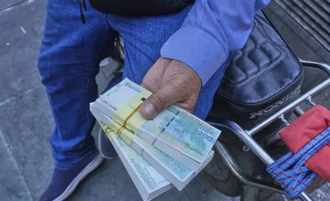 A street money exchanger holds Iranian banknotes at Ferdowsi square, Tehran's go-to venue for foreign currency exchange, in downtown Tehran, Iran, Thursday, Aug. 28, 2025. (AP Photo/Vahid Salemi)