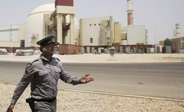 FILE - In this Aug. 21, 2010 file photo, an Iranian security officer directs media at the Bushehr nuclear power plant, with the reactor building seen in the background, just outside the southern city of Bushehr, Iran. (AP Photo/Vahid Salemi, File)
