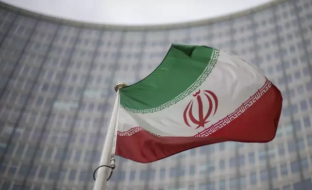 File - A national flag of Iran waves in front of the building of the International Atomic Energy Agency, IAEA, in Vienna, Austria, Friday, Dec. 17, 2021. (AP Photo/Michael Gruber, File)