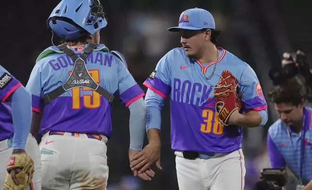Colorado Rockies catcher Hunter Goodman, left, congratulates relief pitcher Victor Vodnik after defeating the Arizona Diamondbacks in a baseball game Friday, Aug. 15, 2025, in Denver. (AP Photo/David Zalubowski)
