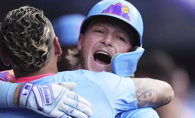 Colorado Rockies' Orlando Arcia, front, hugs Hunter Goodman as he returns to the dugout after hitting a solo home run off Arizona Diamondbacks starting pitcher Brandon Pfaadt in the first inning of a baseball game Friday, Aug. 15, 2025, in Denver. (AP Photo/David Zalubowski)