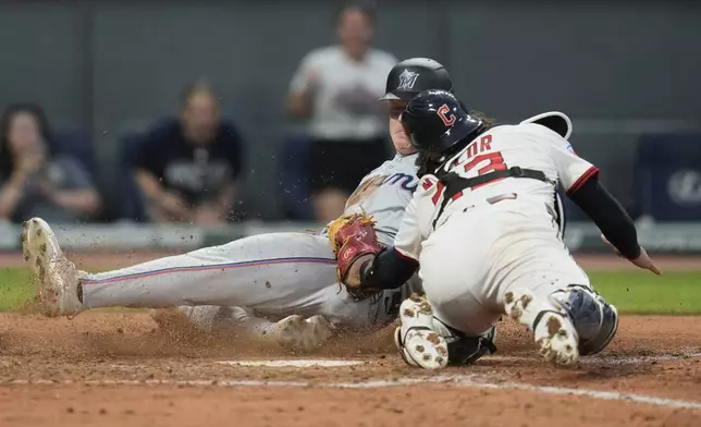 Cleveland Guardians catcher Bo Naylor, right, tags out Miami Marlins first baseman Eric Wagaman, left, at home plate in the sixth inning of a baseball game in Cleveland, Tuesday, Aug. 12, 2025. (AP Photo/Sue Ogrocki)