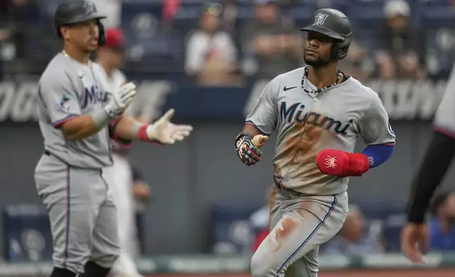 Miami Marlins' Dane Myers, right, scores past Heriberto Hernandez, left, in the fifth inning of a baseball game against the Cleveland Guardians in Cleveland, Tuesday, Aug. 12, 2025. (AP Photo/Sue Ogrocki)
