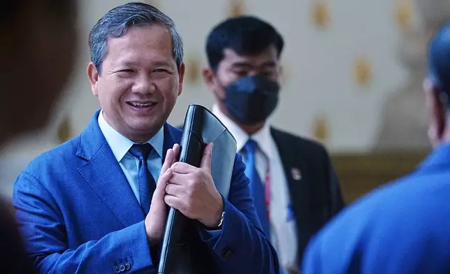 Cambodian Prime Minister Hun Manet, left, greets lawmakers as he arrives at the session on the draft law on amending the law on nationality at the National Assembly in Phnom Penh Cambodia, Monday, Aug. 25, 2025. (AP Photo/Heng Sinith)