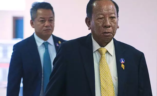 Cambodian lawmaker Tea Banh, right, walks together with his son, Deputy Prime Minister and Minister of National Defense Tea Seiha, left, before the session on the draft law on amending the law on nationality at the National Assembly in Phnom Penh Cambodia, Monday, Aug. 25, 2025. (AP Photo/Heng Sinith)