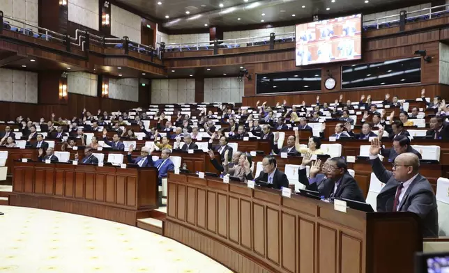 In this photo released by the Cambodia National Assembly, Cambodian lawmakers raise their hands during the session on the draft law on amending the law on nationality at the National Assembly in Phnom Penh, Cambodia, Monday, Aug. 25, 2025. (Cambodia National Assembly via AP)