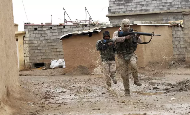FILE - Iraqi Army soldiers secure streets in a recently liberated village occupied by Islamic State militants outside Mosul, Iraq, Thursday, Dec. 1, 2016. Iraqi officials have begun excavation of what is believed to be a mass grave left behind by the Islamic State extremist group during its rampage across the country a decade ago. (AP Photo/Hadi Mizban, File)
