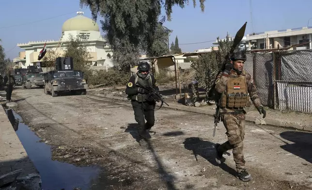 FILE - Iraqi special forces troops advance during a battle against Islamic State militants in Andalus neighborhood in the eastern side of Mosul, Iraq. Iraq, Monday, Jan. 16, 2017. Iraqi officials have begun excavation of what is believed to be a mass grave left behind by the Islamic State extremist group during its rampage across the country a decade ago. (AP Photo/Khalid Mohammed, File)