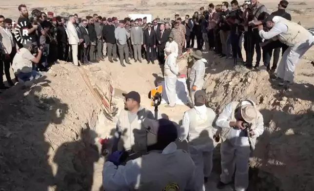 In this image taken from video provided by Rudaw TV, workers dig out human remains at the Khasfa site near the northern Iraqi city of Mosul, where authorities have begun excavating a mass grave believed to contain thousands of victims of the Islamic State (IS) Mosul, Iraq, Sunday, Aug. 17, 2025. (Rudaw TV via AP)