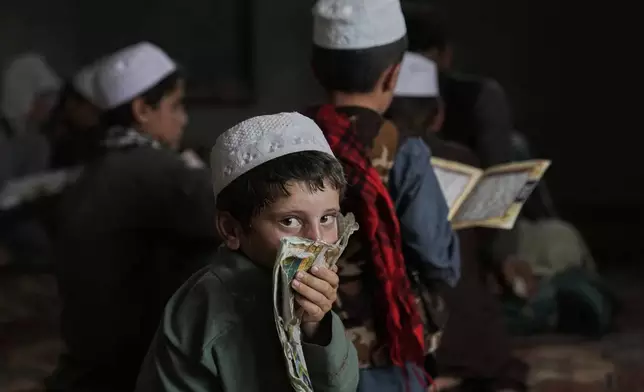 An Afghan boy glances at the camera during a Quran class at the Abdullah Ibn-Masoud religious school on the outskirts of Kabul, Afghanistan, Monday, May 26, 2025. (AP Photo/Ebrahim Noroozi)