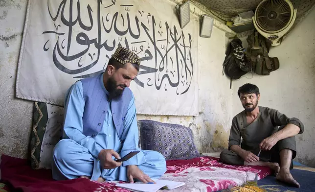 Qari Hizbollah, director of the Imam al-Tirmidhi religious boarding school, left, works with a local baker to count loaves of bread purchased for the school in Kabul, Afghanistan, Wednesday, June 11, 2025. (AP Photo/Ebrahim Noroozi)