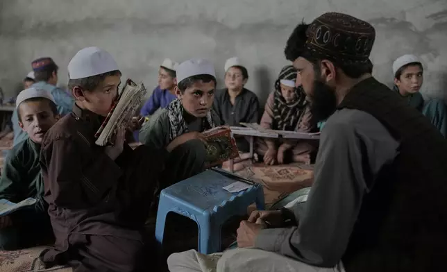 A religious studies teacher instructs Afghan boys in the Quran at the Abdullah Ibn-Masoud religious school in the outskirts of Kabul, Afghanistan, Monday, May 26, 2025. (AP Photo/Ebrahim Noroozi)
