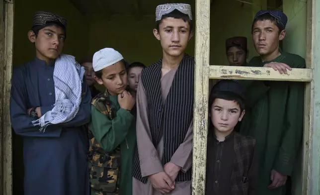 Afghan boys living at the Imam al-Tirmidhi religious school stand by a window frame inside their school in Kabul, Afghanistan, Wednesday, June 11, 2025. (AP Photo/Ebrahim Noroozi)