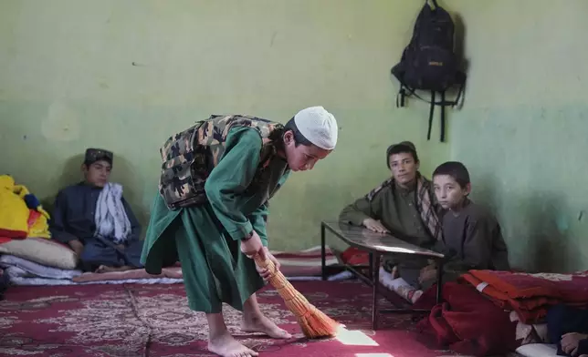 An Afghan boy sweeps the room where he lives and studies at the Imam al-Tirmidhi religious school in Kabul, Afghanistan, Wednesday, June 11, 2025. (AP Photo/Ebrahim Noroozi)