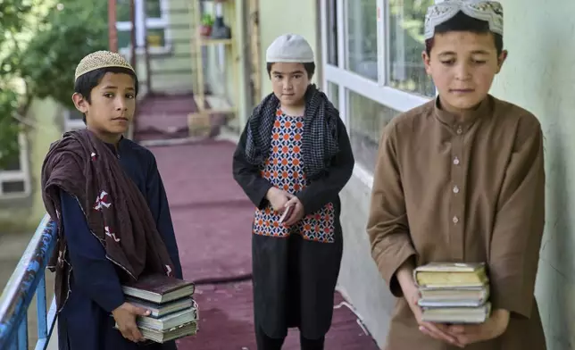 Afghan boys carry copies of the Quran at the Imam al-Tirmidhi religious school in Kabul, Afghanistan, Wednesday, June 11, 2025. (AP Photo/Ebrahim Noroozi)